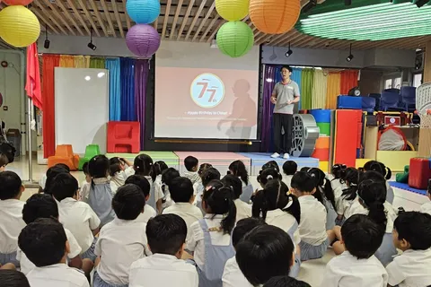 小朋友坐在禮堂內，老師展示慶祝國慶77周年的投影片