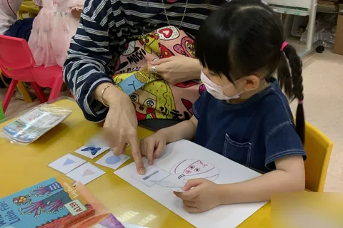 家長指著圖卡，陪伴小朋友完成配對活動