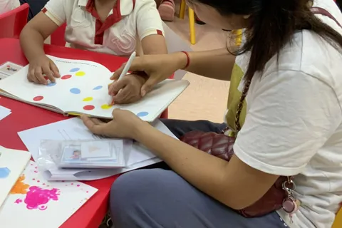 家長和男孩在活動書上沿著彩色圓點描畫