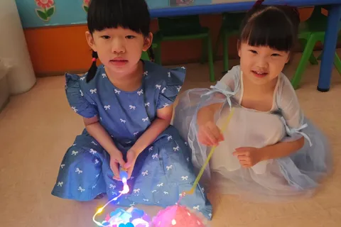 兩位小朋友坐在課室地上，展示發光的花燈
