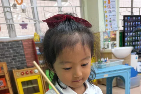 小朋友用長棒攪出黃色的水拓畫紋路