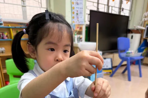 小朋友用小棒在水拓畫盤中攪動紅色和黃色顏料