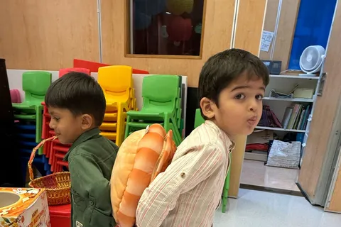 兩位小朋友背對背夾著巨型月餅抱枕前進