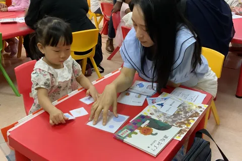 家長和小朋友在紅色桌子上一起配對形狀卡