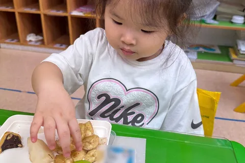小朋友從餐盒中拿起小食