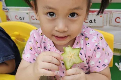 小朋友在小食時間舉起一片楊桃