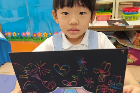 小朋友展示天安門上空綻放煙花的刮畫作品
